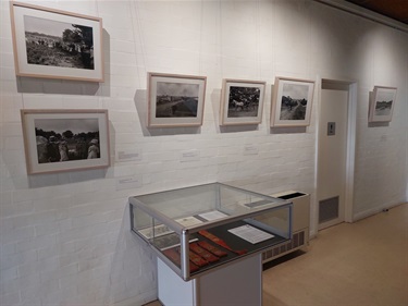 Photographs on the wall and museum cabinet