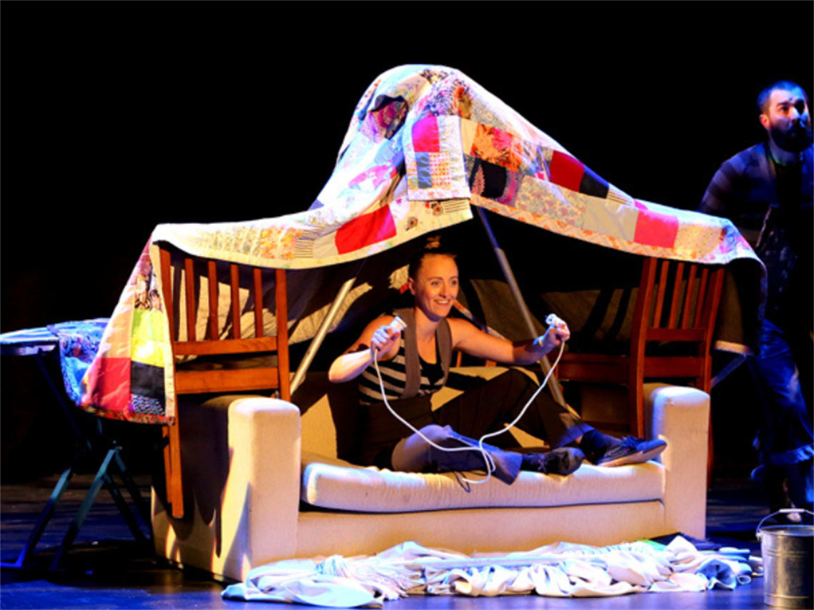 Girl sitting in a home made fort from blankets, chairs, couches and poles