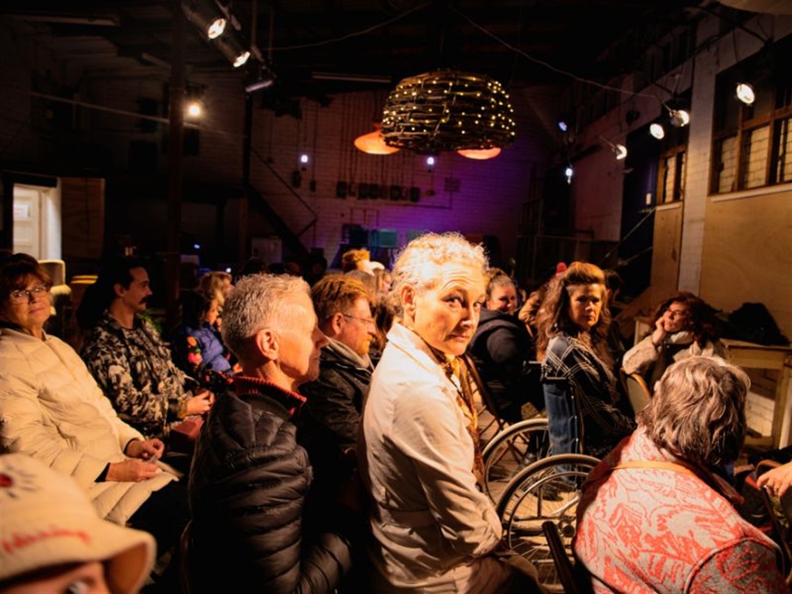 Group of people sitting on chairs in a dark room with minimal lighting