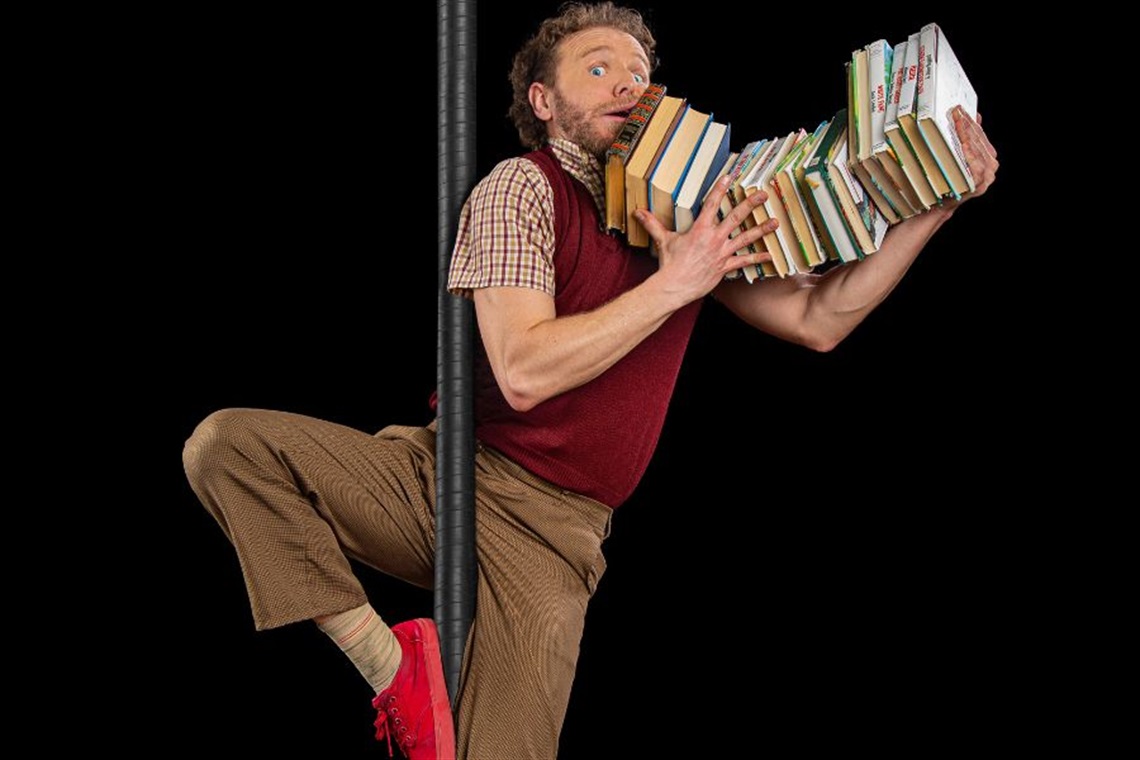 A man sliding down a pole holding books