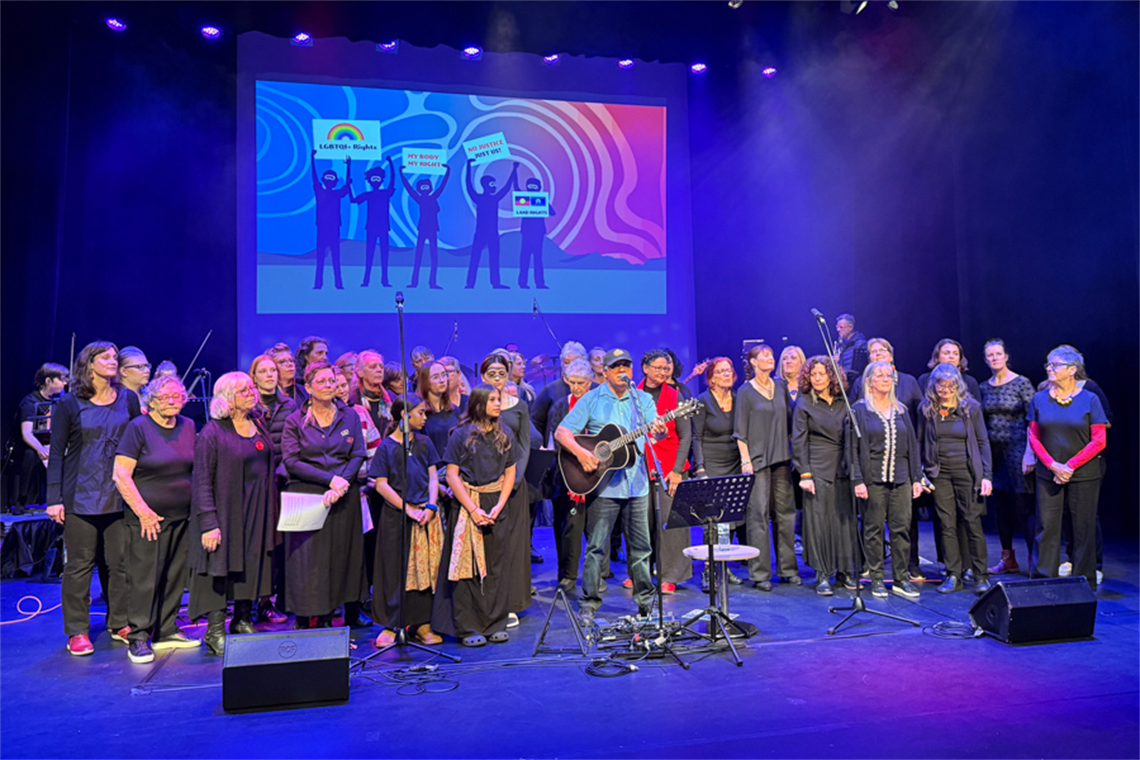 A choir on stage with David Arden