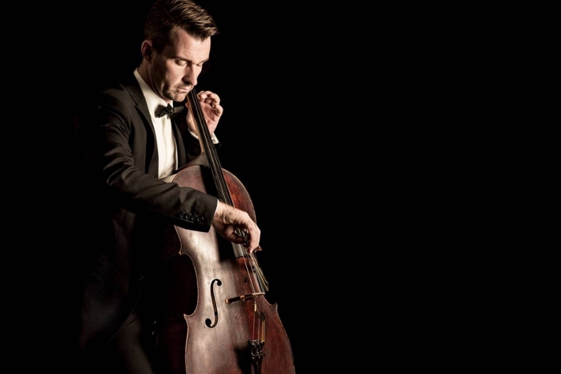 Chris Howlett playing cello against a black background